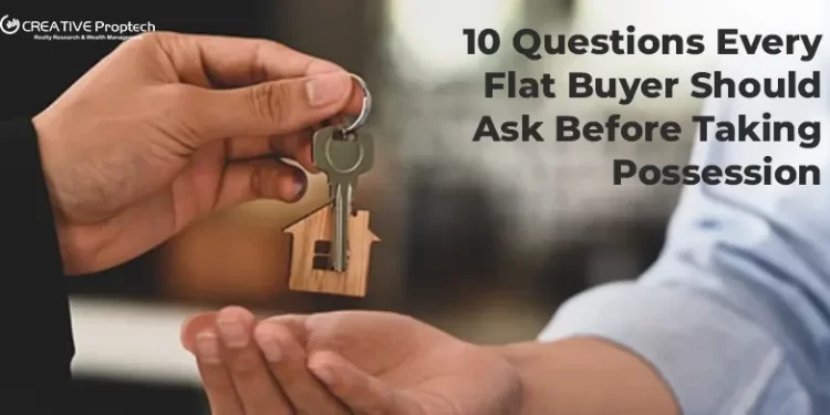 Person handing over house keys with a wooden home keychain to another person with text overlay reads 10 Questions Every Flat Buyer Should Ask Before Taking Possession with CREATIVE Proptech logo.